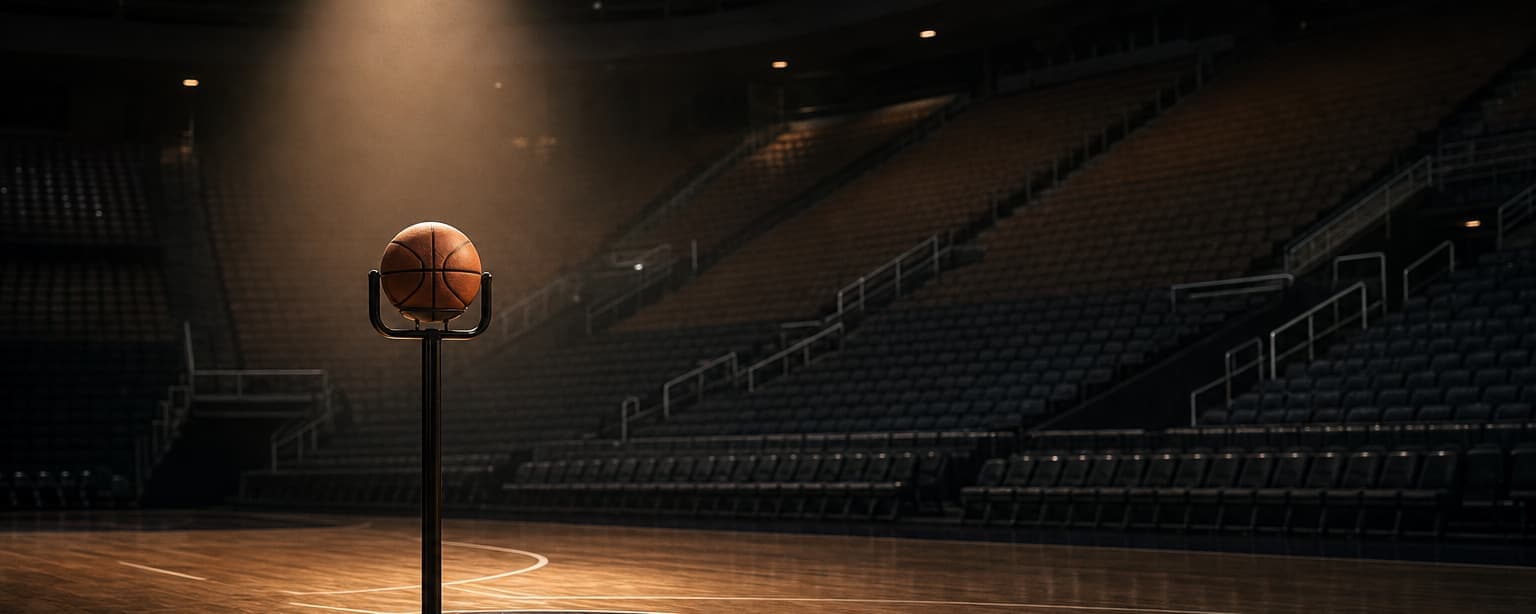 A basketball on a stand at center court in an empty arena, a single spotlight on it and the seating dark behind